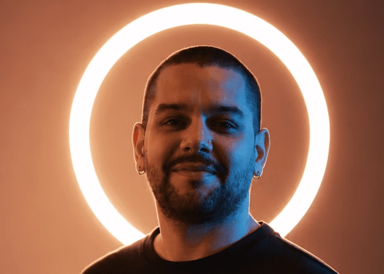 Alexander Ruf smiling in front of a glowing ring light.